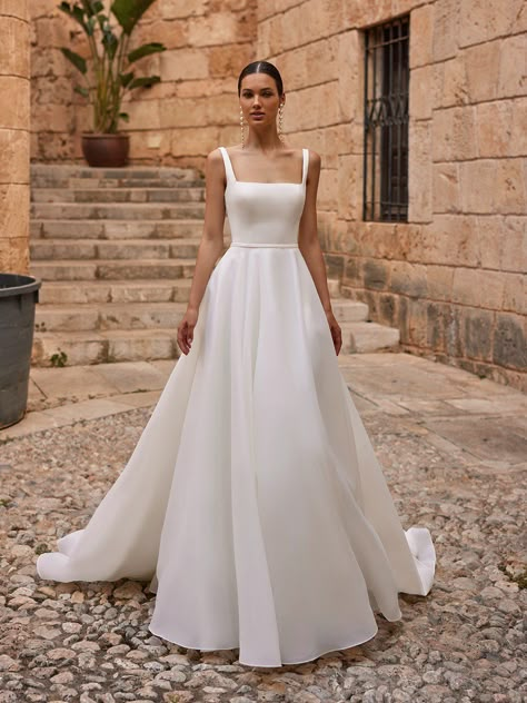 If it’s classic elegance you’re searching for, the Moonlight Tango T133 wedding dress is a luxe choice for your big day. Constructed in organza and satin fabrics that offer contrasting textures, this exquisite gown has a dreamy, ethereal look and feel that’s fitting for a black tie fairytale wedding or a more modern, minimalist event. This design boasts a sleeveless, fitted bodice in smooth satin fabric with a chic square neckline, wide straps that provide comfort and support, and a low scoop Square Neck Wedding Dress, Bodice Wedding Dress, Satin Fabrics, Chic Wedding Dresses, Wedding Dress Organza, Stylish Wedding Dresses, Aline Wedding Dress, Pretty Wedding Dresses, Exquisite Gowns