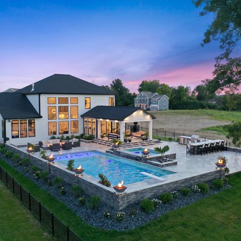 A pool with the works! This gunite swimming pool is surrounded by a spacious travertine patio. The pool includes color changing lighting, a sun ledge, bench seating and laminars. See more: <https://www.pool-fx.com/recent-projects/outdoor-living-at-its-best-westerville-oh> #swimmingpool #gunitepool #outdoorliving Gradual Pool Entry, Inground Pools With Hot Tubs, Big Decks Backyard, Pools Landscaping Ideas, Square Pool With Waterfall, Inground Pool Layout Ideas, Outside Patio Ideas With Pool, Backyard Decor With Pool, Outdoor Living Pool Area