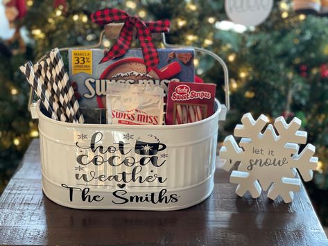 "If you are looking for a great gift for someone who loves hot chocolate in the winter than this white metal caddy is perfect for you! This galvanized caddy has 4 sections- 3 smaller ones in front and 1 larger one in back.  It holds your hot cocoa packets, marshmallows, straws, and peppermint sticks.  The caddy is oval in shape and has a wooden movable handle. The caddy comes with \"Hot Cocoa Weather\" and a family name on the front. This caddy is 10.5\" (L) x 7\" (W) x 5\" (H) without handle & 10\"(H) with handle This listing is for the caddy only.  The hot cocoa ingredients are not included." Gifts With Hot Chocolate Packets, Hot Cocoa Caddy, Hot Chocolate Bar Gift Basket, Hot Chocolate Basket Ideas, Hot Chocolate Gift Basket Ideas, Hot Cocoa Gift Basket Ideas, Hot Cocoa Basket, Family Gift Basket Ideas, Hot Chocolate Gift Ideas