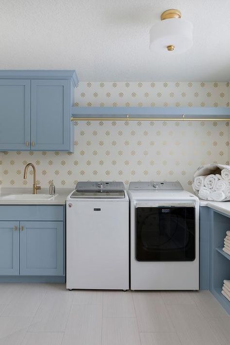 Lovely blue laundry room features a white washer and dryer placed beneath a blue shelf fitted with a brass clothes drying rod. Rod Above Washer And Dryer, White Apron Sink, Laundry Room Cabinet Ideas, Room Cabinet Ideas, Laundry Room Cabinet, Transitional Laundry Room, Traditional Laundry Room, Grey Laundry Rooms, Blue Laundry Rooms