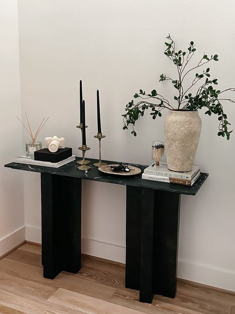 Entryway Console table decor Console Table : Burke Decor Vase : Pottery Barn Plant stems: Amazon Camera Candle : Gift from @kelir from CB2 Diffuser: Pottery Barn Black Candles: Amazon Candle Stand : Gift from @anniemescall Coffee Table Books : Amazon #homedecor #home #entrywaydecor #consoletable #homestyle Black Console Decor Ideas, Hallway Stand Entry Tables, Vase On Entryway Table, Walkway Table Decor, Small Black Entryway Table, Black Console Table Styling, Black Entry Table Decor, Black Coffee Table Styling, Black Console Table Entryway