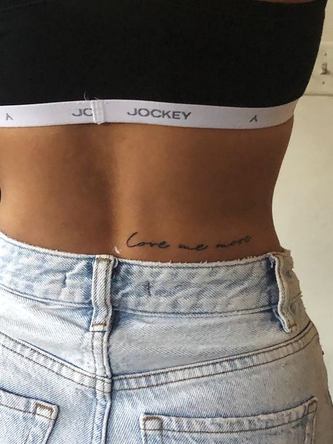 Back script tattoo reading, “love me more” One Worded Tattoos, Waist Back Tattoos For Women, Tattoo Ideas Waist For Women, Lower Back Writing Tattoo, Lower Back Quote Tattoo, Lower Back Script Tattoos, Short Quote Tattoo Placement, Back Tattoo Phrase, Hip Tattoo Script