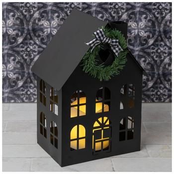 Dimensions: 9.56" H x 6.63" W x 4.75" D Power Source: 3 AAA Batteries (Not Included) Material: Metal, Plastic & Fabric Color: Black, Green & Ivory Pattern: Gingham Care & Safety: Indoor Use Only Quantity: 1 Create a cozy holiday atmosphere by decorating with a cute lantern! Black House Metal Lantern is designed to look like a simple house with a sloping roof, a chimney, arched windows, and a wreath and bow embellishment. Inside the lantern is an LED pillar candle that you can leave off or turn o Cute Lantern, Advent House, Sloping Roof, Tin House, Christmas Lantern, Plastic Fabric, Led Pillar Candle, Seasonal Displays, Cozy Holiday