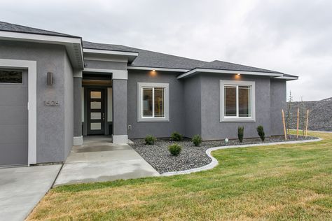 A black front door is an elegant, striking choice that stands out against a grey exterior. Grey Homes Exterior, Grey Paint House Exterior, Grey House Door Color Ideas Exterior, Grey Facade House, Grey Exterior House Colors Stucco, Gray Modern House Exterior, Grey House Paint Exterior, Exterior Grey Paint Colors For House, Grey Stucco Exterior