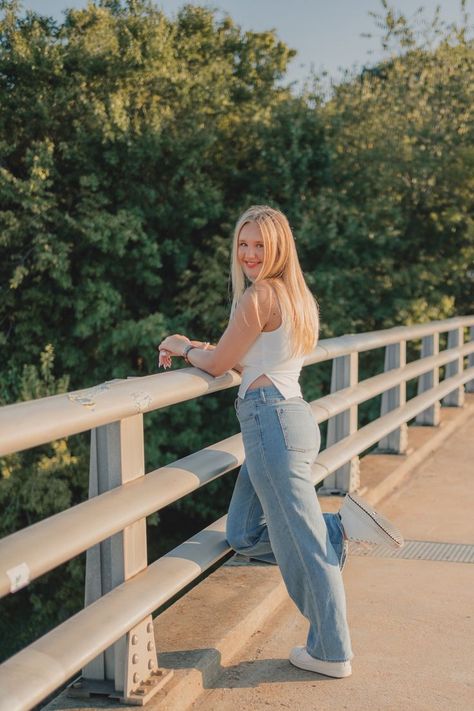 blond teen girl poses with one leg kicked back, smiling over her shoulder at the camera as she leans on a bridge railing. Indoor Senior Pictures, Senior Outfit Ideas, Spring Senior Pictures, Senior Portrait Outfits, Senior Portrait Ideas, Senior Pictures Downtown, Senior Photoshoot Poses, Senior Portraits Girl, Senior Photography Poses