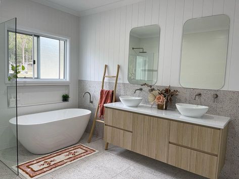 Vertical white shiplap walls create a bright and simple design in this white-themed farmhouse bathroom. The half-shiplap wall is accompanied by a gray-speckled terrazzo tile backsplash. Position a red and white vintage mat with a matching towel draped over the wooden ladder leaning nearby the bathtub to add a striking visual piece. Vj Panelling And Tile Bathroom, Vj Panelling Bathroom With Tiles, Vj Panelling Bathroom, Panelling Bathroom, Brushed Nickel Tapware, Vj Panelling, Neutral Bathroom Ideas, Nickel Tapware, Calming Bathroom