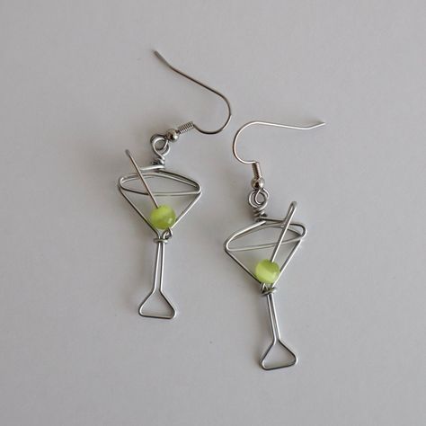 Martini Glass Earrings. Great gift for Bartenders, Hostesses and Waitresses. NOW AVAILABLE IN TWO SIZES. Regular martini glass is 1 1/2 inches high, small martini glass is 1 1/8 inches high (not including earring hooks, see inset photo for scale). Tiny wire martini glasses, complete with green cat's eye bead.  Surgical steel hooks are hypo-allergenic. Clear plastic stoppers on backs. Aluminum wire will not tarnish. I have been making custom wire art and jewelry for 30 years. I started in 1989 se Martini Wire Earrings, Wire Wine Charms, Stud Wire Earrings, Wire Earring Designs, Christmas Wire Jewelry, Wire Earring Ideas, Unique Diy Earrings Ideas, Wire Earrings Diy, Selfmade Earrings