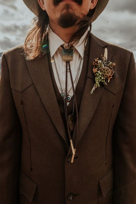 Western inspired wedding day attire for this stylish boho groom. | Photo by Maggie Grace Photography #westernwedding #bohowedding #wedding #mountainwedding #boho #bohogroom #groom #groomfashion #poseideas #groompose #groomportrait #bolotie #weddingcolors #fall #fallwedding Mens Wedding Attire Woods, Boho Tuxedo Men, Vintage Wedding Attire For Men, Men’s Vintage Wedding Attire, Bohemian Mens Wedding Attire, Groom Vintage Attire, Mens Boho Suit, Mens Tuxedo Wedding Boho, Eclectic Mens Wedding Attire