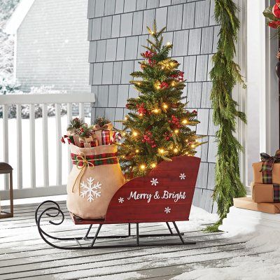 Bring the magic of the holiday season into your home with the Member's Mark™ 46” Pre-Lit Wooden Sleigh with Topiary. Perfect for indoor display or for adding a festive touch to your covered porch, this sleigh is sure to captivate everyone with its charm. The elegant red wooden sleigh, resting on two curled metal rails, houses a mini-Christmas tree adorned with 70 warm white LED lights, 11 pinecones, and 11 red berries. Also included is a burlap sack with three gift boxes and two candy canes, adding to the festive feel. Joy Decorations, Wooden Sleigh, Warm White Led Lights, Christmas Front Porch, Christmas Porch Decor, Christmas Sleigh, Front Porch Christmas Decor, Christmas Yard, Christmas Style