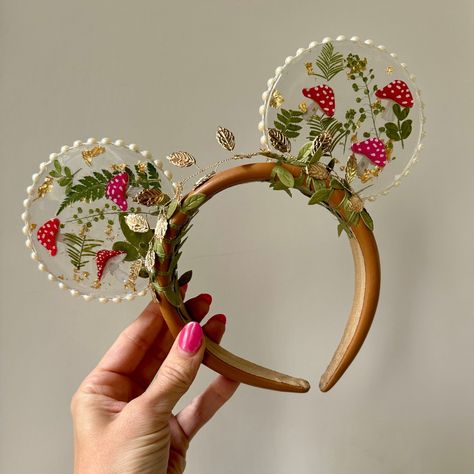 For all the Cottagecore girlies! These resin mouse ears are unique and fun, with an earthy vibe and a touch of glam, perfect for any fairy princess 🍄🧚. A neutral headband is accented with a gold leaf crown and vines, and the mushrooms and greenery stand out in clear, shiny resin, sparkly with flecks of gold and finished with pearl trim. A perfect complement to your theme park outfit, these whimsical ears are lightweight and absolute show stoppers. Our mouse ears are intended for women and adul Princess Disney Ears, Aesthetic Mickey Ears, Custom Disney Ears, Cute Disney Ears, Disney Ears Diy, Cottagecore Mouse, Theme Park Outfit, Mushroom Aesthetic, Gold Leaf Crown