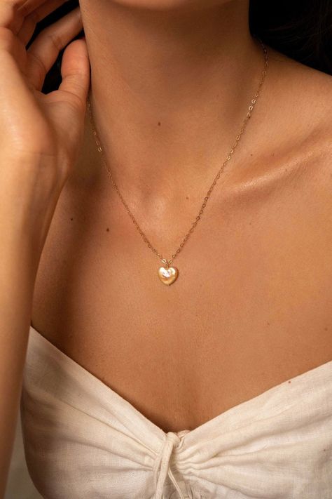 The Lise pearl heart necklace is handcrafted with a heart shaped freshwater pearl and a delicate heart chain. A perfectly classic romantic piece, easy to dress up or down.  14K gold-filled heart chain Heart-shaped freshwater pearl Hypoallergenic, suitable for even the most sensitive skin Each piece is delivered in a silk bag inside a gift box Sustainable packaging   Please note, as we use only natural pearls, shape and size may vary slightly.  We offer a one year guarantee from the date of deliv Pearl Heart Necklace, Abercrombie Girls, Chain Heart, Silk Jewelry, Silk Bag, Pink Quotes, Pearl Heart, Bag Inside, Heart Chain