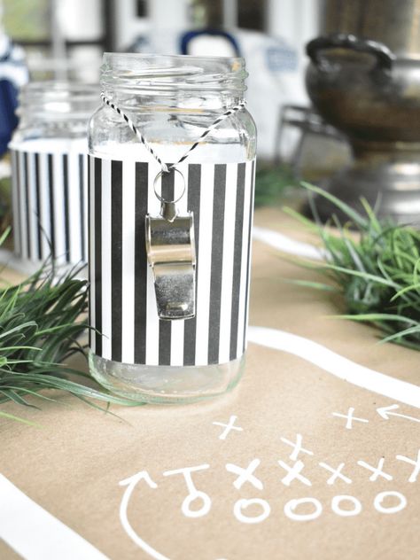 I had so much fun creating this football themed tablescape for my dinner club this month! I used lots of things I already had on hand and got creative with ways to use them for this tablescape. A memorobilia football helmet that my husband had, an old football, a yellow scarf turned into "penalty" flag napkins, and black/white striped paper and whistles to create "referee" glasses made perfect accents for my table. Read along and I'll show you how I created this tablescape on a budget. Football Table Scape, Sport Table Decorations, Sports Themed Retirement Party, Football Party Tablescape, Classy Football Decor, Sports Table Decorations, Boho Football Party, Tailgate Centerpiece Ideas, Football Bridal Shower Theme