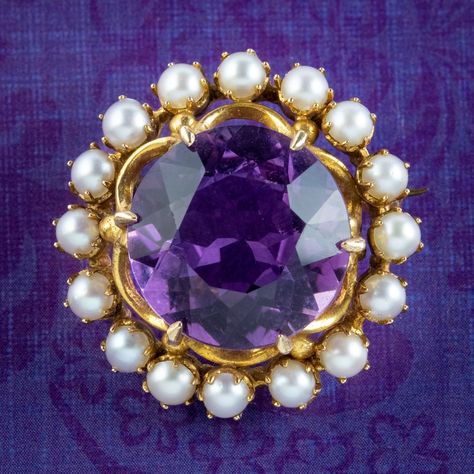 A glorious antique Edwardian brooch from the early 1900s built around a sizable amethyst in the centre, weighing approx. 20ct. It has a deep, regal purple hue and is complemented by a halo of bright, white pearls around the outside.   Amethyst is the birthstone of February. It's considered a stone of protection, clarity and tranquillity and has been highly esteemed throughout the ages for its stunning beauty and deep purple colouring which has adorned regal jewellery all around the world, from a Amethyst Brooch, British Crown Jewels, Drawing Bases, Edwardian Jewelry, Ornate Design, Wedding Brooch, Blue Topaz Earrings, Antique Brooches, Silver Lockets