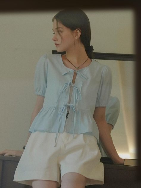 Blouse in an airy woven cotton fabric. Round neckline, an open front with ribbon ties, and short puff sleeves. Gently flared peplum.  - Regular length- Short sleeves- Peplum- Round neck Ribbon Top Outfit, Korean Blouse Outfit, Soft Blue Outfit, Puff Sleeves Outfit, Tie Front Top Outfit, Peplum Top Outfits, French Trip, Vietnam Clothes, Ribbon Blouse