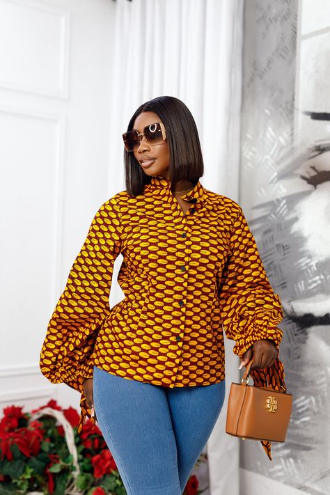 Make a statement in the ELIZA African Print Puff Sleeve Shirt! Perfect for the office or your next event, this top can be worn with a skirt, pants or jeans for a stylish look appropriate for any occasion. Rock this trend-worthy piece and keep your style up-to-date for the season. FEATURES.* 100% African Wax Cotton* Tied-Puff sleeve design* Unlined Button up shirt.* Model Is Wearing A Size Medium and 2X-Large.CARE INSTRUCTION* Hand Wash in Cold Water.* Do Not Bleach.* Press with Cool Iron on The African Print Skirt And Top For Office, African Shirt And Trouser For Women, Ankara Casual Tops, African Shirts For Ladies, Trending Two Piece Outfits, Ankara Tops Blouses With Jeans, African Tops For Women Classy, African Print Tops With Jeans, Ankara Tops For Women