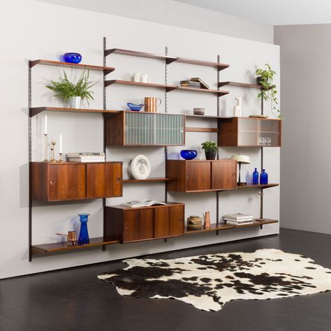 An elegant and functional shelving system in rosewood designed by Kai Kristiansen in the 60s and manufactured by FM Mobler is an impressive four-bay entirely modular set. The preserved manufacturer's label validates its origin.  Five cabinets and thirteen shelves provide enough space for storage, books, and decorations. The wall unit features brilliant carpentry and a rich wood grain of rosewood veneer with solid wood details. Each section is 86cm wide, and one can arrange all the parts as neede