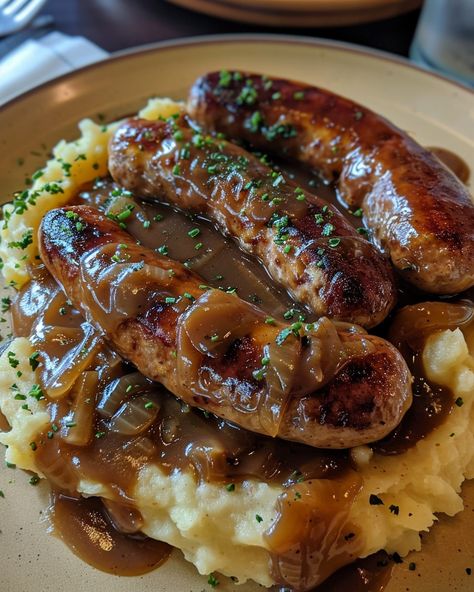 Classic Bangers and Mash with Rich Onion Gravy Ingredients: 8 pork sausages (traditional British bangers) 4 large potatoes, peeled and cut into chunks 4 tablespoons unsalted butter 1/2 cup milk (or more, as needed) Salt and pepper, to taste For the Onion Gravy: 2 large onions, thinly sliced 2 tablespoons unsalted butter 2 tablespoons all-purpose flour 2 cups beef or chicken broth 1 tablespoon Worcestershire sauce Salt and pepper, to taste Instructions: Step 1: Cook t... British Food Recipes, British Bangers, British Meals, Mashed Potatoes With Gravy, British Food Traditional, Daftar Menu, Sausage And Mash, Sausage And Potatoes, Pork Sausages