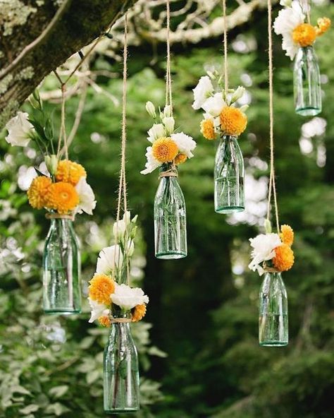 The clear glass bottle can be beautiful to be used as a hanging vase. You can hang the bottles on the tree with some pretty flowers there. If you want the durable one, you can have the fake flowers. Bottle Vases from @luksbazaar Glass Bottles Plants, Glass Bottle Wedding Decor, Glass Bottle Garden Ideas, Bottle Vases With Flowers, Hanging Glass Bottles, Fake Flowers In Vase, Hanging Flower Vase, Hanging Glass Vase, Wedding Party Decorations Diy