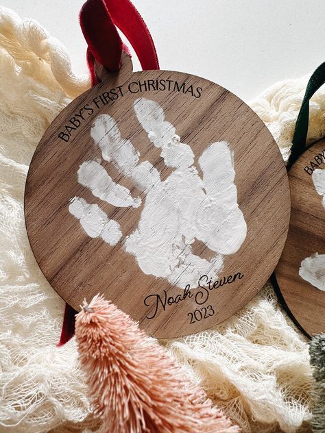 "This is the perfect handprint Christmas ornament keepsake to remember those little handprints forever! Have us engrave their name and date at the bottom of the ornament and if this is their first Christmas we can engrave, \"Baby's First Christmas\" at the top as well.  Choose from Light Maple or Dark Walnut wood. Choose from 3 velvet ribbons: Red, Green or Gold. (Paint is NOT included but any acrylic paint works great on our wood ornaments.) Choose from 3 different sizes: Small: Will fit a hand Handmade Baby Ornaments, Baby Homemade Ornaments, Christmas Gifts From Newborn, Baby Handprint Ornament Paint, Infant First Christmas, Baby Feet Ornament Diy, Baby Craft Ideas Christmas, Baby Christmas Keepsakes Diy, Baby Craft Christmas Gifts