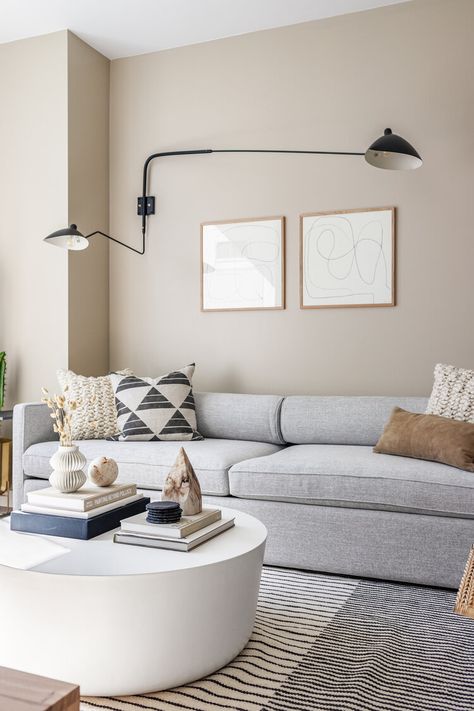 Neutral living room with beige walls, grey sofa, white concrete coffee table, abstract wood framed art and black double sconce above sofa. Living Room Design Beige, Grey Sofa Living Room Ideas, Beige And Grey Living Room, Greige Living Room, Gray Sofa Living, Grey Walls Living Room, Grey Sofa Living Room, Living Room Wall Color, Room Wall Colors