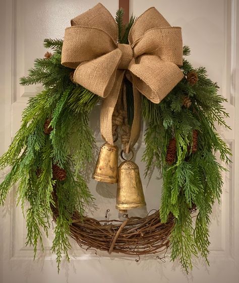 Rustic Harmony Bells, make beautiful music, and complete this Christmas, Winter, Holiday wreath, framed in realistic faux cedar and pine boughs, pinecones, with a burlap bow.  This grapevine wreath base is 18"L X 16"W, and the Rustic Harmony, cone shaped Cow Bells, with wooden strikes, are hand made in India, and add the perfect touch to your holiday decor. Winter Wreath With Church, Country Barn Wreath, Wooden Wreaths Rustic, Western Xmas Wreaths, Burlap And Pine Cone Wreath, Rustic Burlap Christmas Wreath, Hunting Wreath Rustic, Pine Wreath Base, Llbean Wreaths