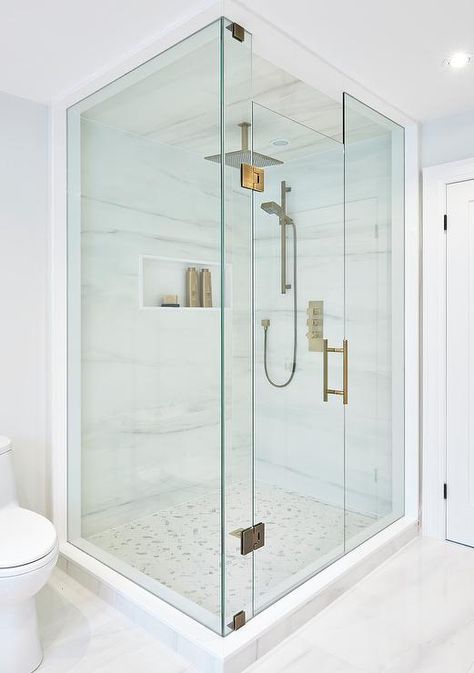 Perfectly designed seamless glass shower is fitted with marble herringbone floor tiles complementing marble walls that frame a niche and hold a modern brass shower kit paired with square rain shower head mounted to a marble clad ceiling. Floor To Ceiling Shower Door, Homemade Tiles, Clad Ceiling, Herringbone Shower Floor, Brass Rain Shower Head, Marble Herringbone Floor, Herringbone Shower, Mosaic Shower Tile, Marble Walls