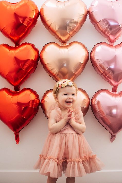 Baby girl wearing pink dress claps hands in front of heart balloon background. Diy Valentines Backdrop Photography, Valentine Cake Smash, Valentines Sibling Photos, Toddler Valentine’s Day Photo Shoot, Valentines Diy Photoshoot, Siblings Valentines Photoshoot, Diy Valentines Photo Shoot Toddler, Valentine’s Day Minis, Valentines Toddler Photoshoot