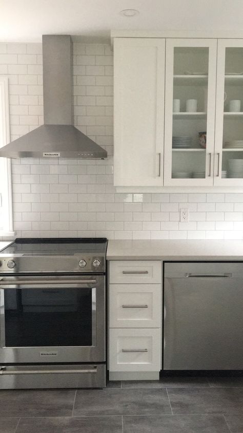 White kitchen featuring white shaker cabinets, caesarstone london grey quartz countertops, echo floor london grey flooring, white subway tile from Rona, kitchenaid appliances White Kitchen Cabinets Gray Floor, Grey Floor Kitchen Ideas, White Cabinets Grey Countertops, Light Grey Quartz Countertops, Grey Quartz Countertops Kitchen, Caesarstone London Grey, Light Grey Countertops, Grey Quartz Countertops, Walnut Interior