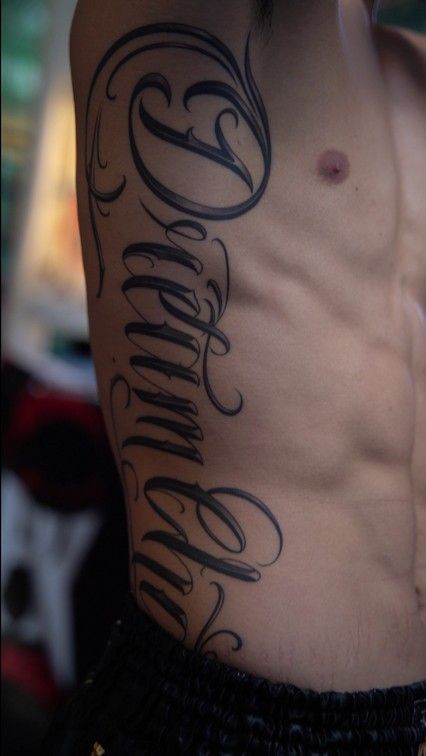 Side Tattoos Men Ribs Guys, Cursive Rib Tattoo Men, Neck Text Tattoo Men, Last Name Tattoos For Men On Back, Ready To Die Tattoo, Name Tattoo Ribs, Rib Lettering Tattoo, Last Name Back Tattoos For Men, Lettering Back Tattoo