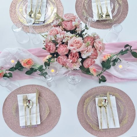 Indulge in the allure of an appealing wedding table setup. Pink and white sheer organza table runners, adorned with a faux leaf garland, create a whimsical touch atop the pristine white polyester tablecloth. Clear round charger plates rest elegantly on rose gold shimmer tablemats, adding a touch of glamour. Gleaming gold plastic utensils and crisp white dinner napkins grace the charger plates, inviting guests to partake in a delightful feast. Organza Table Runner, Event Decor Ideas, Party Decorations Table, Wedding Table Setup, Flowers Candles, Plastic Utensils, White Dinner, Faux Leaf, Leaf Garland