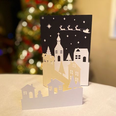 Create your own festive Holiday cards with this Christmas Village Scene SVG files. This template makes beautiful Greeting Cards and is a great project for the whole family! #seasongreetings #holidaycard #christmascard #christmasvillage #christmascene #santasleigh #wintertown #holidaygreeting #christmassvg #holidaycardtemplate #christmascardtemplate #diychristmascard #winterwonderland #diyholidaycard #stampinup #stampinupcards #cricut #cricutmade #cricutcreated #cricutsvg #svg #svgfiles #svgfiles Christmas Invitations Ideas Handmade, Silhouette Cameo Christmas Cards, Intricate Christmas Cards, Christmas Village Cards, Paper Cut Christmas Cards, Cricut Christmas Cards Ideas, Christmas Card Cricut, Christmas Cards Cricut, Diy Christmas Cards Cricut