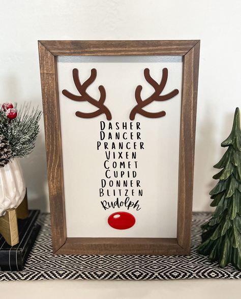 This 3D and laser engraved Reindeer name sign is the perfect addition to any Christmas decor. It is made to stand on its own so it styles well on entry tables, counter tops, shelves, mantles, etc. It has about 1/2 inch over hang that would allow it to hang on walls as well.  Materials: The frame is made from premium pine The Sign is made on a high quality MDF backer board with engraved lettering and laser cut acrylic antlers and nose The Sign pictured is 8x12 THE SIZE IS THE ENTIRE SIGN TOP TO BOTTOM INCLUDING THE FRAME *NO HANGING HARDWARE IS INCLUDED **PLEASE NOTE THAT EACH PIECE OF WOOD HAS DIFFERENT NATURAL CHARACTERISTICS SUCH AS CRACKS, KNOTS AND TEXTURE. THIS CAUSES SLIGHT VARIATIONS IN HOW THE STAIN ABSORBS. EACH FRAME IS UNIQUE. Reindeer Tree Theme, Rudolph Christmas Tree Theme, Christmas Picture Decor, Reindeer Names Sign, Diy Christmas Wall Art Craft Ideas, Reindeer Porch Sign, Christmas Wall Collage Ideas, Reverse Canvas Christmas Signs, Funny Holiday Signs