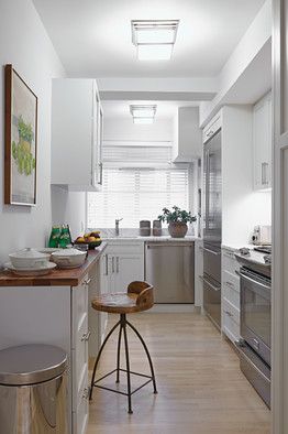 "In a galley kitchen, it's a waste of space to just have an empty wall across from the cooking area," explained Mr. Doherty. His solution: a walnut-topped prep surface that switch-hits as a coffee-sipping spot. The counter adds an organic touch to the white-on-white scheme—and, together with a cabinet positioned asymmetrically above it, a certain weight to the sidewall. "This brought a sense of balance and doubled the usable area," he said. Narrow Kitchens, Enclosed Kitchen, Long Narrow Kitchen, 3d Kitchen Design, Small White Kitchens, Transitional Doors, Kitchen Transitional, Galley Kitchens, Narrow Kitchen