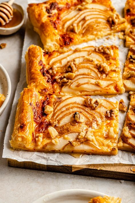 Gorgeous pear puff pastry tart with spicy cheddar cheese, toasted walnuts, and a drizzle of honey. This delicious, easy pear tart recipe makes the perfect appetizer for impressing friends & family and takes just 15 minutes to prepare! Serve warm or at room temp and watch guests devour. #appetizer #pears #puffpastry #newyearseve #holiday Persimmon Puff Pastry, Pear Puff Pastry, Ambitious Kitchen Recipes, Holiday Tarts, Pear Desserts, Pear Tart Recipe, Savoury Bites, Fancy Foods, Entertaining Appetizers