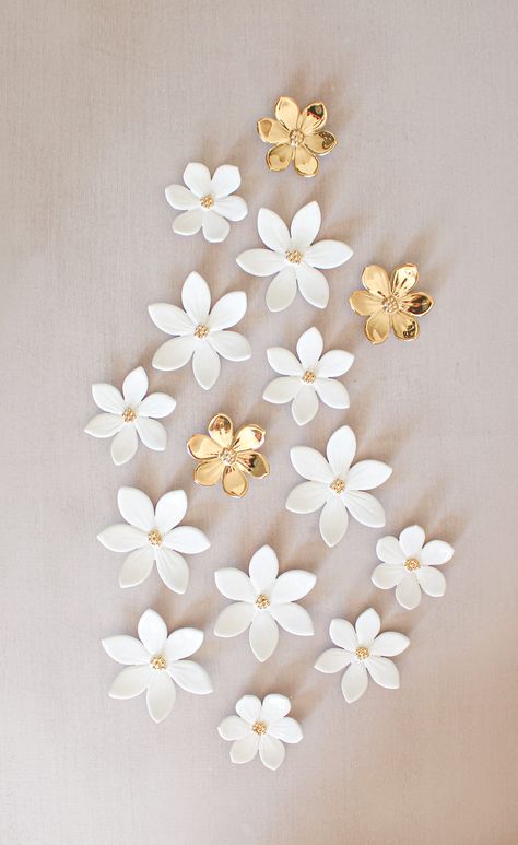 A little variation on our white decor!  We offer 15 ceramic flowers for wall decoration.  The color is a shiny white and a center of 24k gold mini beads.  We added 3 small all-gold flowers for a bright touch.  Breakdown:  6 flowers around 8cm  (3.14 in.)  3 flowers around 7cm (2.75 in.)  3 flowers around 6 cm (2.36 in.)  3 flowers around 6cm all gold ( 2.36in)  To hang them on the wall or on your panel, there are 2 small loops at the back. Please consider any customs fees  Feel free to reach out if you have any questions.  All our flowers are handmade in our studio.  o¨o¨o¨o¨o¨o¨o¨o¨o¨o For further informations concerning shipping and packing : https://www.etsy.com/fr/shop/LysaCreationDesign/policy#seller-info?ref=shopinfo_seller_information_leftnav Flowers For Wall, Ceramic Star, Flowers For Home, Kids Bedroom Walls, Ceramic Wall Decor, Clay Wall, Playroom Wall Art, Gold Ceramic, Clay Flowers