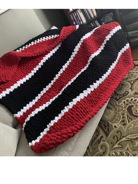 The Georgia Bulldogs chunky knit blanket is a bold and cozy piece perfect for fans of the team. The blanket features thick, oversized yarn that is hand-knit, giving it a luxurious and plush texture. The primary color is a deep, rich red, representing the Georgia Bulldogs' iconic color, with bold black and white stripes or accents woven into the design to further emphasize the team's spirit. 60"X62" The blanket's chunky stitches create a visually appealing and tactile pattern, adding to its warmth and comfort. It's large enough to be a perfect companion for game days, whether at home or in the stadium, offering both style and coziness. This blanket is not only practical but also a statement piece, embodying the fierce pride and loyalty of Georgia Bulldogs fans. Chunky Blanket Pattern, Chunky Knit Blanket Pattern, Chunky Yarn Blanket, Chunky Blankets, Football Blanket, Giant Yarn, Yarn Blanket, Go Dawgs, Chunky Crochet Blanket