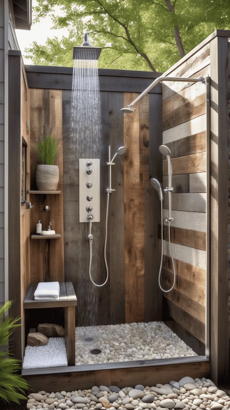 Combine modern elegance with rustic charm in this private backyard outdoor shower. Encased in weathered wood and featuring sleek fixtures, this shower brings a spa-like ambiance to your outdoor space. Surrounded by river rocks and nestled against a backdrop of reclaimed wood panels, it offers a harmonious blend of contemporary design and natural elements, creating a serene retreat for a luxurious shower experience. Outdoor Shower Ideas Private Modern, Natural Rock Shower Floor, Outdoor Shower Cabin, Outdoor Shower Rustic, Rustic Outdoor Bathroom Ideas, Outdoor Bathroom Design Nature, Modern Outdoor Shower Ideas, River Rock Shower Floor Ideas, Bamboo Outdoor Shower Ideas