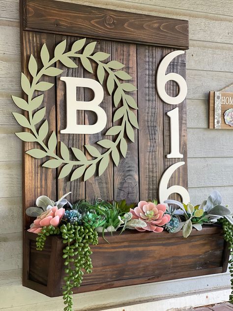 "Our beautifully handmade address planter boxes are sure to bring warmth and charm to any home or office. These handmade address plaques are a unique way to display your address while adding charm with the planter box attached. Our planters are sure to brighten any entrance of your home or office.  Our address planter boxes are made from carefully selected wood. You choose your choice of stain or just leave it natural. Add up to 5 numbers to your planter box. Each planter box is sealed to be protected against the weather and its elements. Our planter boxes are designed for either real or artificial plants or flowers. Flowers are not included unless otherwise custom ordered. The address plaque can also be personalized with last name initial inside a leaf reef just custom order and we will s Planter Box Porch, Planter House Number, Planter Boxes In Front Of House, Address Planter Box Diy, Small Back Porch Decorating Ideas, Diy House Number Sign, Planter Sign, House Number Planter, House Number Ideas