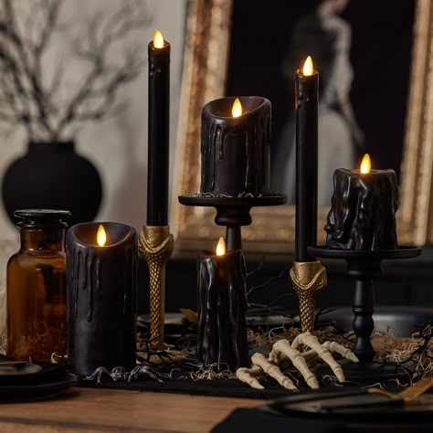 Add a dark touch to your home decor with the Black Wax Drip Flameless Candle Pillar. The flameless light shimmers against the black wax with realistic "drippings" like a candle from an abandoned mansion. Despite the appearance, this candle never melts--instead, it flickers for years to come. Arrange this candle with other pillars in varying sizes or make it the centerpiece of a tray or candelabra. This eerie pillar accentuates Halloween decorations, like pumpkins, spiderwebs and carved skulls. Y Black Skull Decor, Candle Sconces Decor Ideas, Candle Aesthetic Dark, Dark Candle Aesthetic, Halloween Party Table Setup, Goth House Decor, Halloween Candle Decor, Whimsy House, Halloween Wedding Decorations