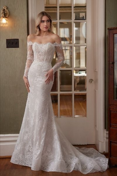 Step into a bygone era of timeless elegance with our vintage-inspired fitted wedding dress, Talisa. Her delicate off-the-shoulder long sleeves evoke a sense of old-world romance, while her exquisite floral lace overlay adds a touch of ethereal beauty to every movement. Designed with a modest straight neckline, this gown exudes grace and sophistication. And with meticulous button details adorning her high back and the cuffs of her long sleeves, the allure of this dress is simply irresistible. Modest Neckline Wedding Dress, Calla Blanche Wedding Dress, Statement Wedding Dress, Calla Blanche, Sheath Wedding Dress Lace, Cape Wedding Dress, Bridal Elegance, Vintage Wedding Dress, Long Sleeve Wedding Dress Lace