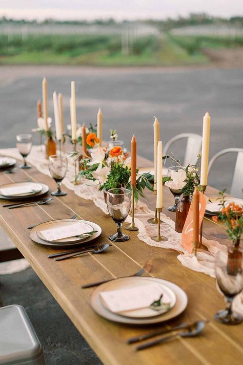 Mid Century Modern Farmhouse Wedding Inspiration Wedding garland tablescape with brass candlesticks. #weddinginpso #tablescape #weddingdecor #rusticwedding Farmhouse Long Table Decor, Wedding Tables With Brass Candlesticks, Candlestick Wedding Table, Colored Candlesticks Wedding, Diy Table Arrangements, Vintage Vases Wedding Table, Colorful Candlesticks Wedding, Stoneware Wedding Table, Long Table Centerpieces For Wedding