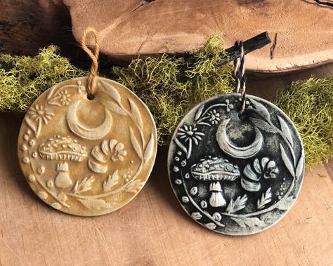 Ceramic Strega Ornament, Nature Ornament for Christmas, Solstice, Yuletide.The perfect gift for your witchy woman or nature lover! These hand-pressed strega ornaments feature a crescent moon, horn, amanita mushroom, calendula, oregano, mugwort, and bay laurel designed for yuletide magick. Chose from Black or Golden over an off-white clay body. Back is unglazed. Large round ornament measures 3.5" diameter. Ornament is lightweight, hung from golden wool yarn, or black and tan jute.All ornaments ar Winter Solstice Gifts, Winter Solstice Party, Yule Crafts, Pagan Christmas, Pagan Yule, Amanita Mushroom, Bay Laurel, Pottery Ornaments, Black Magick