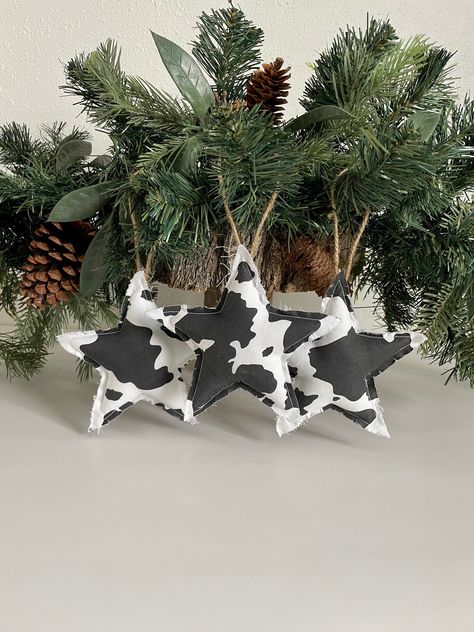 "Set of 3 Primitive Star Ornaments. Cow Print Star Decorations. Cow Christmas Ornaments. Stars are 6\" X 6\".   Set includes: 3 black and white cow print stars. Stars have a 7\" jute hanger. These will hang from tree branches, garland, or decorative hooks. Stars are cut in a primitive style with a rag edge, minimal fraying may occur. The ornaments are stuffed with poly fill for a plump look. These are a perfect touch to your holiday decor!  *If you would prefer no jute hangers, please add that t Diy Farm Animal Ornaments, Diy Cow Christmas Decor, Western Holiday Decor, Boho Western Christmas Decor, Cow Print Christmas Decor, Diy Western Ornaments, Cowboy Christmas Decor, Cow Hide Crafts, Cow Themed Christmas Tree