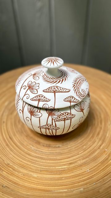 Ceramic Artist, Zahava Friedman on Instagram: "Among the Wildflowers   Wheel thrown ceramic jar with freehand sgrafitto illustration using laguna red bmix clay and amaco velvet white underglaze.   . . . #pottery #ceramicart #handmade #potterylovers #sgraffito #maker #cerámicas #art #liddedjar #sgraffitopottery #ceramicstudio" Sgraffito With Underglaze, Wheel Throwing Pottery Ideas, Underglaze Drawing, Sgrafitto Ceramics, Underglaze Ceramics, Amaco Underglaze, Underglaze Pottery, Ceramic Sgraffito, Sgraffito Designs