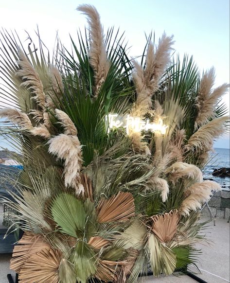 Mix of dried and green palm leaves with touches of pampas grass Palms And Pampas, Dried Palm Leaves Decor Wedding, Pompass Grass Backdrop, Dry Leaves Decoration Ideas, Palm Leaves Decoration Wedding, Paper Palm Leaves Backdrop, Dried Palm Leaves Wedding, Pampas Grass And Palm Leaves, Palm Leaves Backdrop