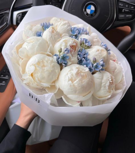 a bunch of flowers sitting in a white vase on top of a car steering wheel