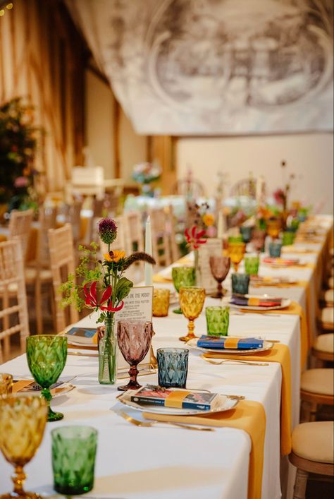 Tablescape using multi-coloured goblets and tumblers, gold napkins and whimsical floral displays in mismatched vases. #Wedding #Tablescape #Colorful #Gold #Barn #Summer #Design #WeddingStyle 📸 Zara Davis Mismatched Dinner Plates Wedding, Mismatched Table Setting Mix Match, Eclectic Wedding Place Settings, Mismatched Dishes Wedding, Mismatched Plates Dinner Party, Colorful Wedding Plates, Coloured Glassware Wedding, Mix And Match Wedding Tables, Multicolored Glassware Wedding