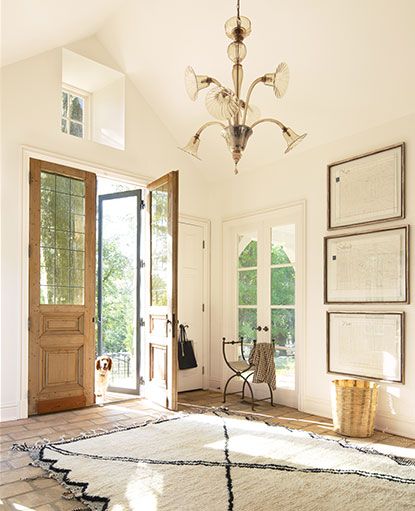 A white painted entryway in Capri Coast OC-87 features vaulted ceilings and a chandelier. Bm Navajo White Walls, Benjamin Moore Navajo White Walls, Bm Linen White Walls, Bm Navajo White, Bm Linen White, Linen White Paint, Backyard Flooring, Painted Entryway, Benjamin Moore Linen White