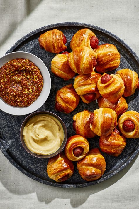 Making the iconic crowd-pleaser doesn’t get easier than with this recipe of mini smoked cocktail sausages (or petit hot dogs) wrapped in store-bought buttery pastry. Prepared crescent roll dough does a lot of heavy lifting here, but you can use puff pastry if you prefer. Served as part of a full-out spread for the Super Bowl, a Monday game day, holiday fête, or weekend get-together, this classic party appetizer will likely disappear as quickly as you put it out, so be prepared to make plenty. Sausage In Pastry, Mini Hot Dogs In Crescent Rolls, Puff Pastry Hot Dog, Sausage Puff Pastry, Sausage Pastry, Easy Pigs In A Blanket, Mini Hotdogs, Mini Sausages, Smoked Cocktail