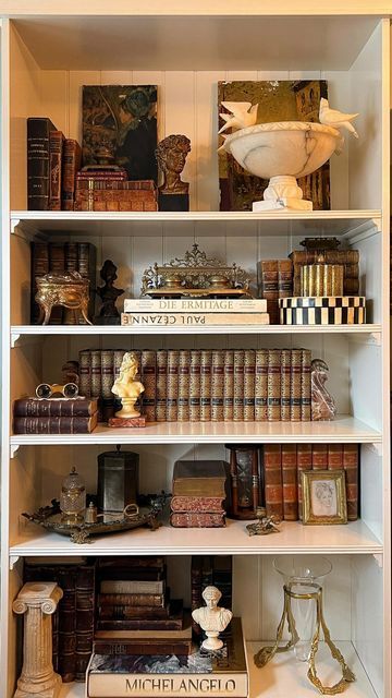 Antique & Vintage Home by Veronica Ashley on Instagram: "Style my vintage shelves with me ✨ It was time to transform my shelves back to a former version of themselves— with some updates, of course! Layering my own curated collection of vintage and antique treasures on these shelves gives me so much joy and I wanted to share that process with you. Stay tuned as I am back this week (and next) with lives sales lined up! So many more vintage and antique treasures to come. Follow along for more vintage and antique hauls, shop collections, live sales and more! ✨ Xx Veronica . . . . . #vintagedecor #shelfstyling #antiquelove #vintagehomedecor #onlinevintageshop #vintagehaul #shopvintage #curatedvintage #smallbusiness #vintageshop #antiquesofinstagram #estatesalefinds #thriftedandstyled #myc Bookshelf Ideas Vintage, Wall Bookcase Decor, Vintage Book Shelf Ideas Aesthetic, Decorating Shelves With Antiques, Victorian Shelf Decor, Antique Shelves Display Ideas, How To Style Office Shelves, Vintage Bookcase Styling, Parisian Shelves